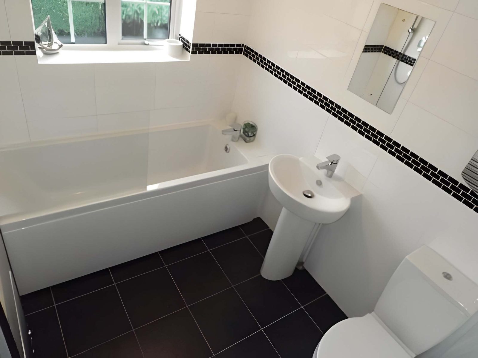 Tiled bathroom with bath, basin and WC