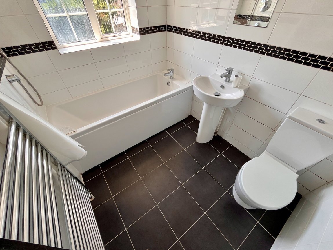 Tiled bathroom with bath and shower, basin, WC and towel radiator