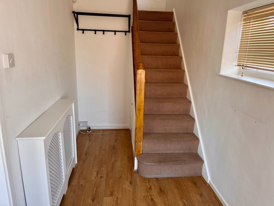 Hallway with wood-effect floor and carpeted stairs